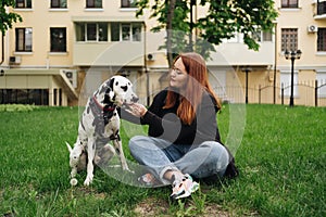 Pretty woman posing and hugging dalmatian dog on street city background