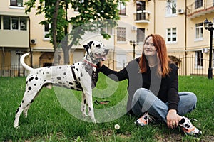 Pretty woman posing and hugging dalmatian dog on street city background