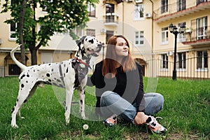 Pretty woman posing and hugging dalmatian dog on street city background