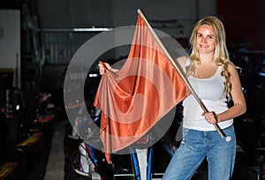 Pretty woman with race flag standing near car
