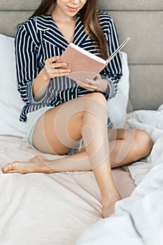 Pretty woman reading book in bed at home
