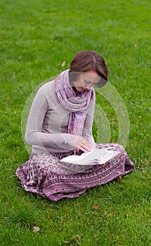 Pretty woman reading a book on a grass