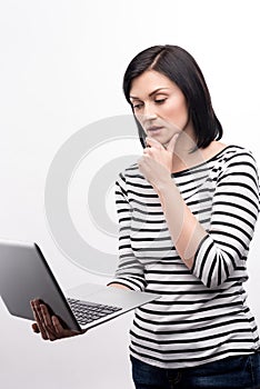 Pretty woman reading from laptop and touching her chin