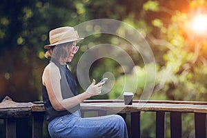 pretty woman reading message in smart phone with coffee cup on wood table