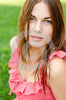 Pretty woman in red dress sitting on park