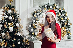 Pretty woman in red dress standing near and christmas tree