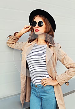 Pretty woman with red lips wearing fashion black hat sunglasses coat over grey