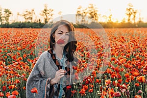 Pretty woman with red poppy in flower meadow.