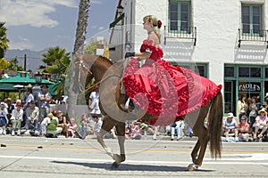 Pretty woman with a red Spanish dress on horseback during opening day parade down State Street, Santa Barbara, CA, Old Spanish Day