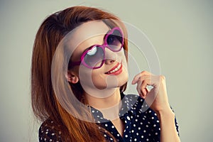 Pretty woman in red sunglasses smiling over green grey background