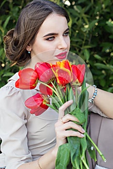 Pretty woman with red tulips sitting on the bench