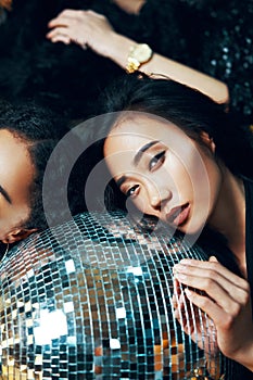 Pretty woman relax and lying down on the floor on disco ball in nightclub after crazy party