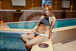 Pretty woman relax at the side of pool indoors