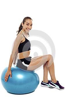 Pretty woman relaxing on big blue exercise ball