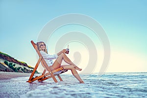 Pretty woman relaxing on a lounger beach and drinks soda water. summer vacation concept