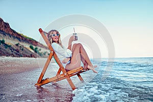 Pretty woman relaxing on a lounger beach and drinks soda water. summer vacation concept