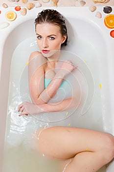 Pretty woman relaxing in milk bath with flowers