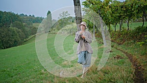 Pretty woman relaxing vine field rainy autumn day. Carefree girl holding grape