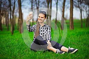 Pretty woman resting in park and take selfie on phone. Concept of communication and leisure time