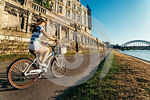 Pretty woman ride bicycle on embankment of Wisla river