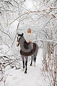 Pretty woman riding her horse through snow country road