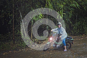 pretty woman riding small enduro motorcycle crossing shallow creek