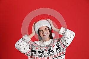 Pretty woman in Santa hat and Christmas sweater on red background