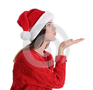Pretty woman in Santa hat and red sweater blowing kiss on white background