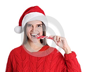 Pretty woman in Santa hat and red sweater eating candy cane on white background