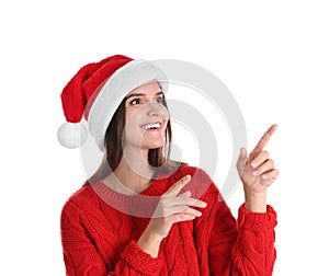 Pretty woman in Santa hat and red sweater pointing on white background