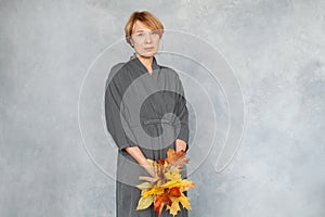 Pretty woman with short ginger hair holding autumn maple leaves, portrait
