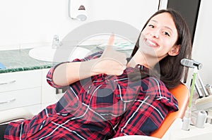 Pretty woman showing thumb up in dentist chair