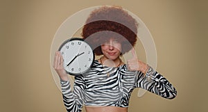 Pretty woman showing time on wall office clock, ok, thumb up, approve, pointing finger at camera