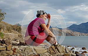 Pretty woman sits on the seashore and looks afar.