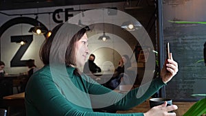 Pretty woman sitting in cafe and talking. Green dress with long sleeves