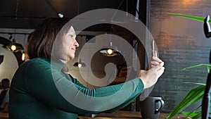 Pretty woman sitting in cafe and talking. Green dress with long sleeves