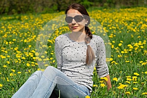 pretty woman sitting on dandelions field. Relaxing woman posing on spring blooming meadow. springtime concept