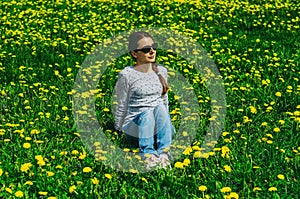 pretty woman sitting on dandelions field. Relaxing woman posing on spring blooming meadow. springtime concept