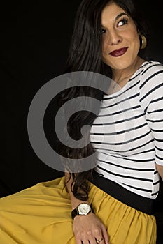 Pretty woman sitting down yellow skirt black background