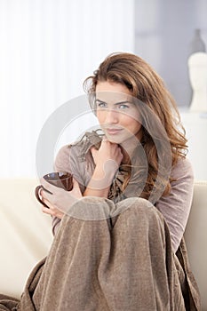 Pretty woman sitting on sofa drinking tea