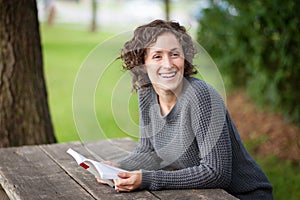 Pretty woman smiling to somebody behind her. She is at a picnic table photo