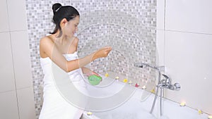 Pretty woman sowing spa salt on bathtub