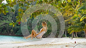 Pretty woman spends her vacation at the seaside. Sexy hot daring girl is swinging on a swing. Concept natural beauty