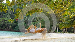 Pretty woman spends her vacation at the seaside. Sexy hot daring girl is swinging on a swing. Concept natural beauty