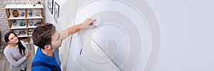 Repairman Installing Smoke Detector On Wall