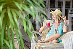 Pretty woman with straw hat sitting in the tropical shade