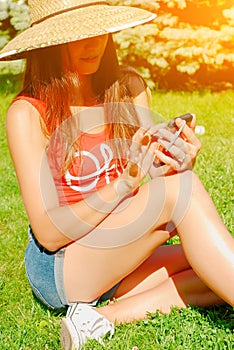 Pretty woman in straw hat speaks via smart phone with relatives