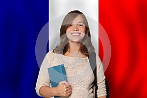 Pretty woman student against French flag background. Travel, education and learn language in France concept