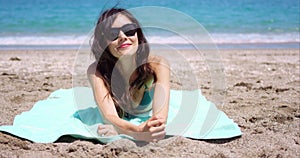 Pretty woman in sunglasses sunbathing on a beach