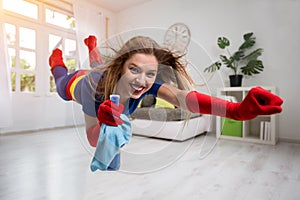 Pretty woman superhero flying through the room with a mop